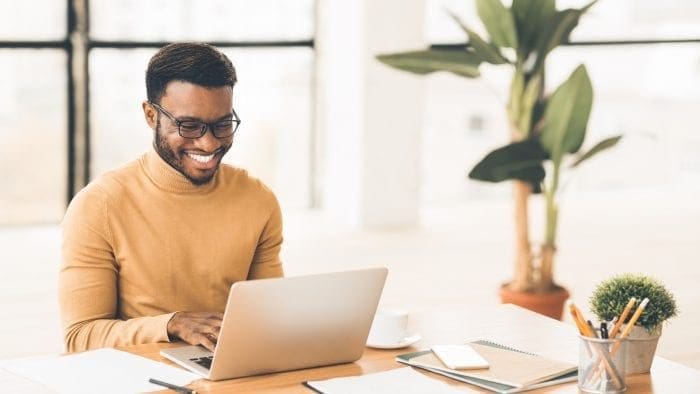 Man at desk smiling at laptop